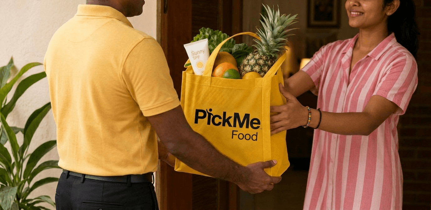 Delivery rider handing a PickMe Food grocery bag to a customer at her door