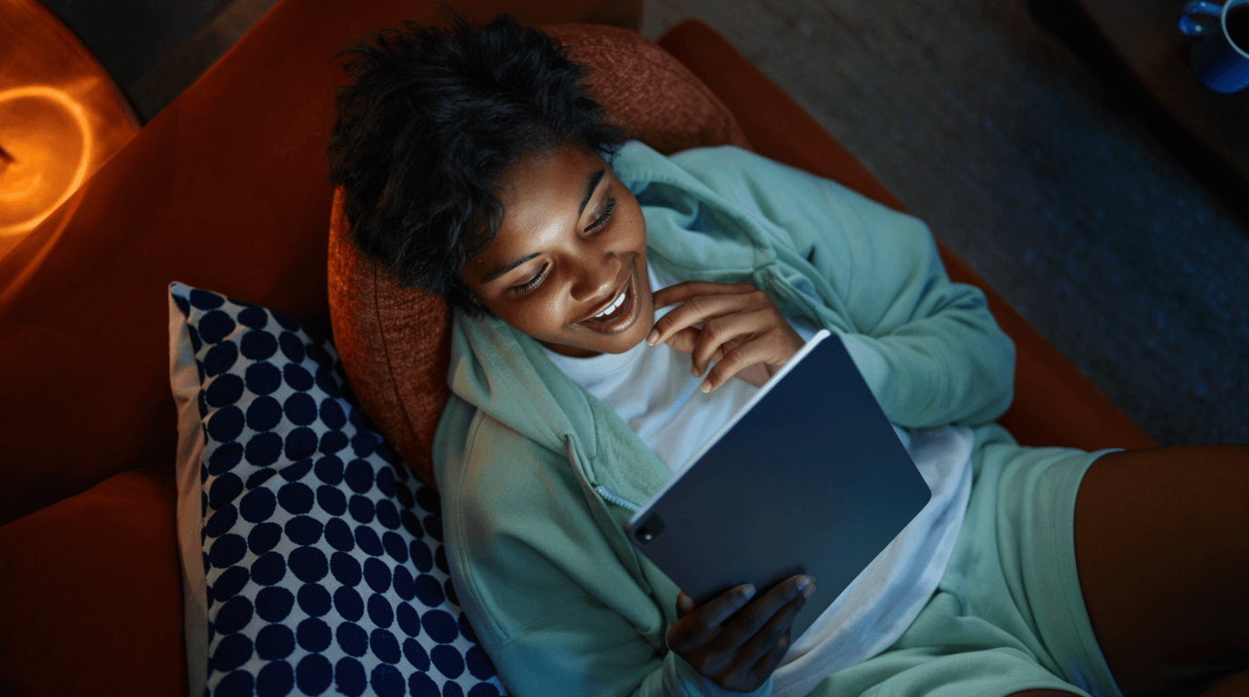 Woman relaxing on a sofa while watching content on a tablet